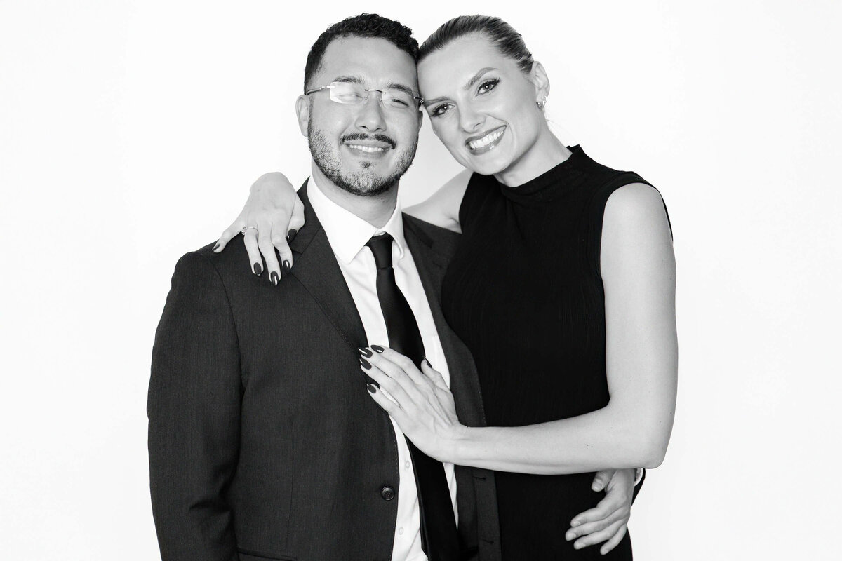 Couple dressed in formal attire smiling together in a black and white portrait captured by Monochrome Portraits, a luxury portrait station in Phoenix.