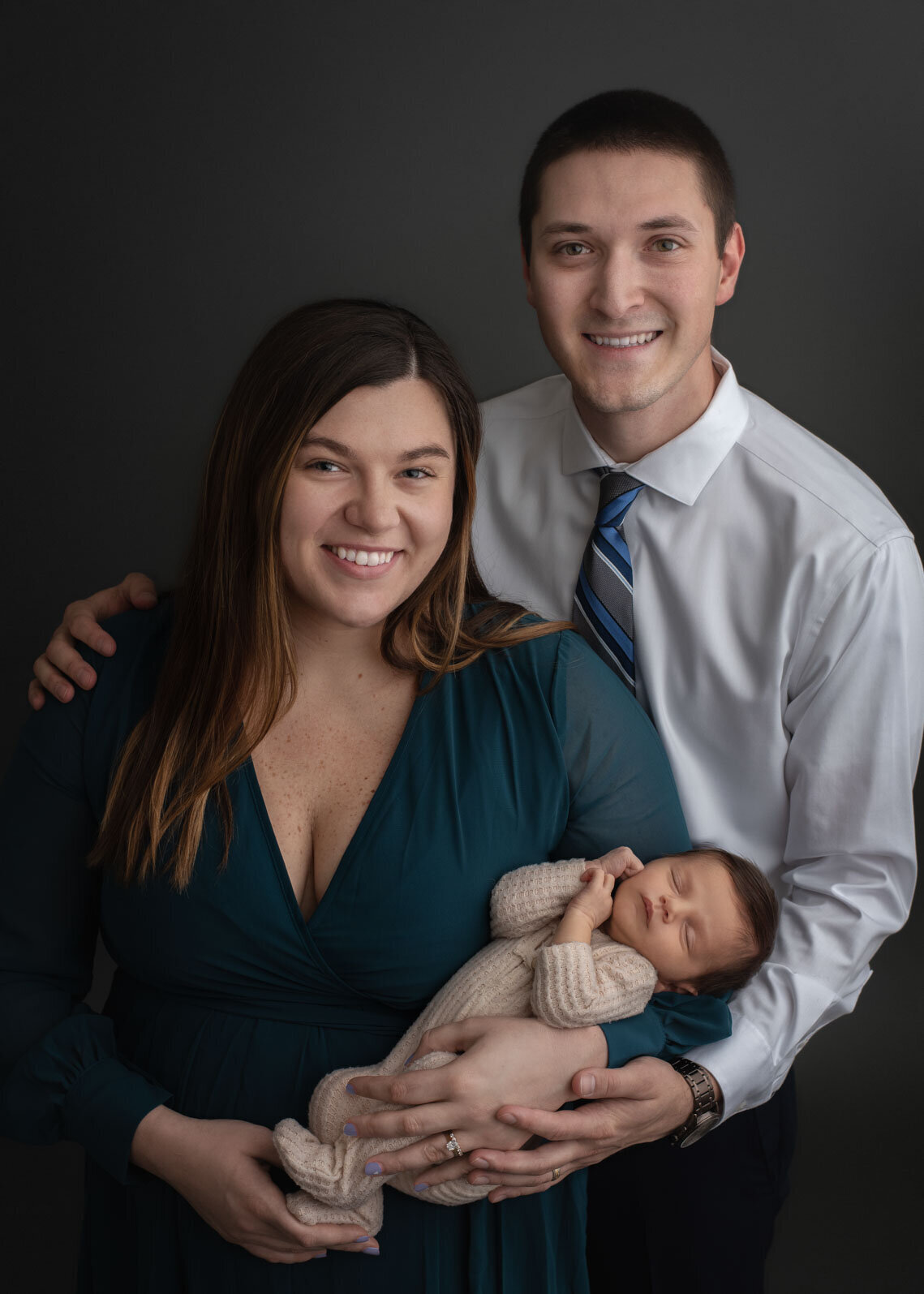 parents smiling at camera and holding baby at their st louis newborn session