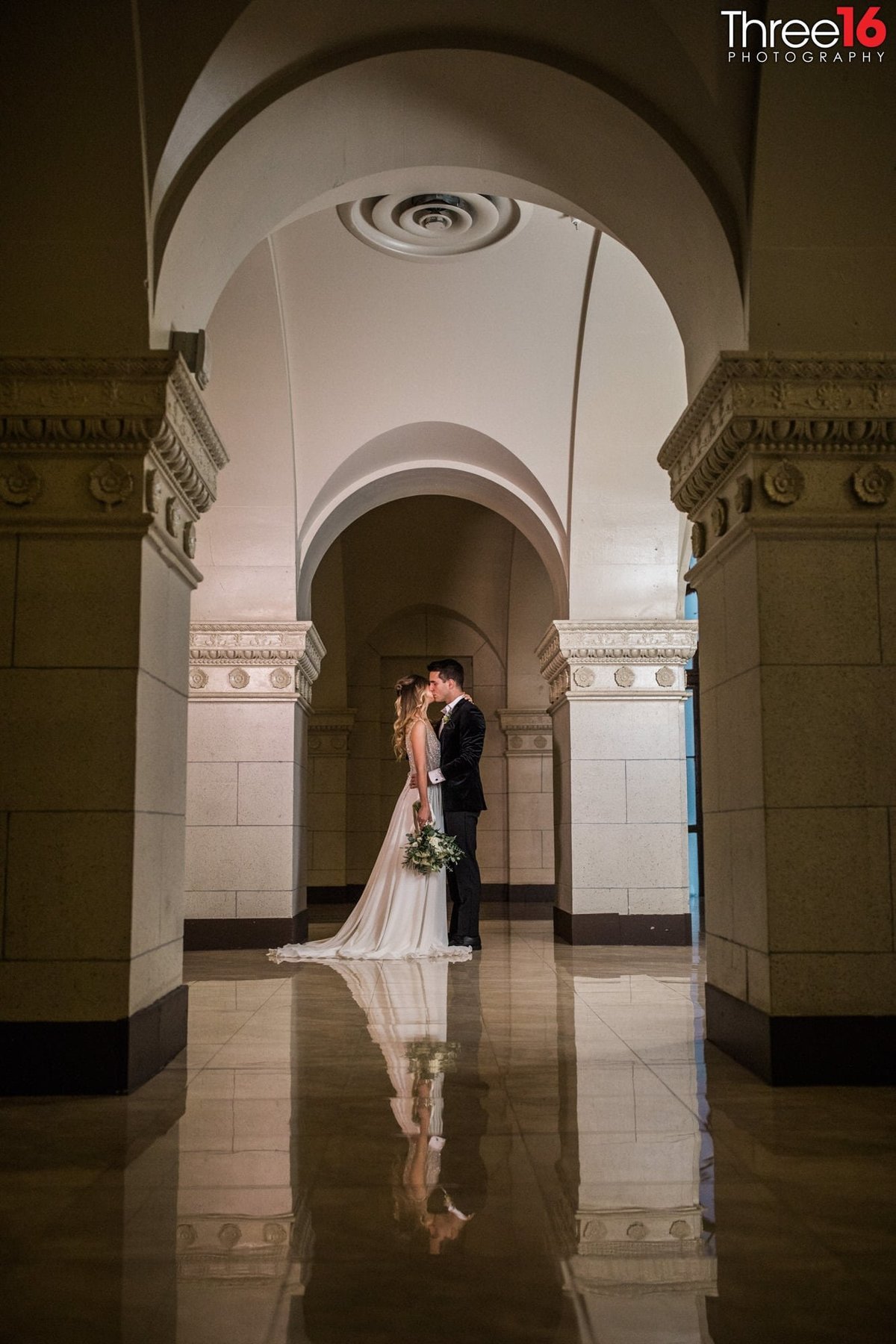 Newly married couple share an intimate kiss under the archway ceiling
