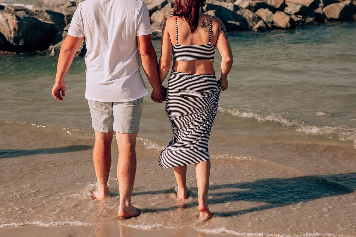couple entering the new smyrna beach water holding hands