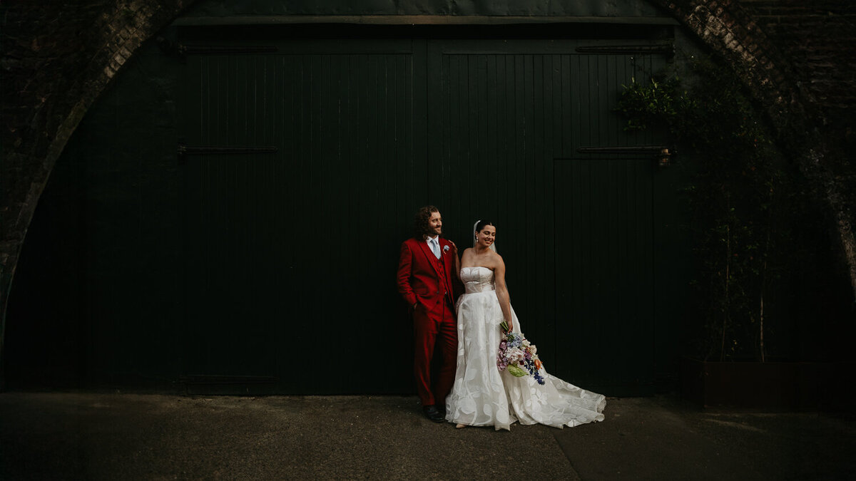 A bride and groom stand outside their wedding venue at 100 Barrington in Brixton, London. 