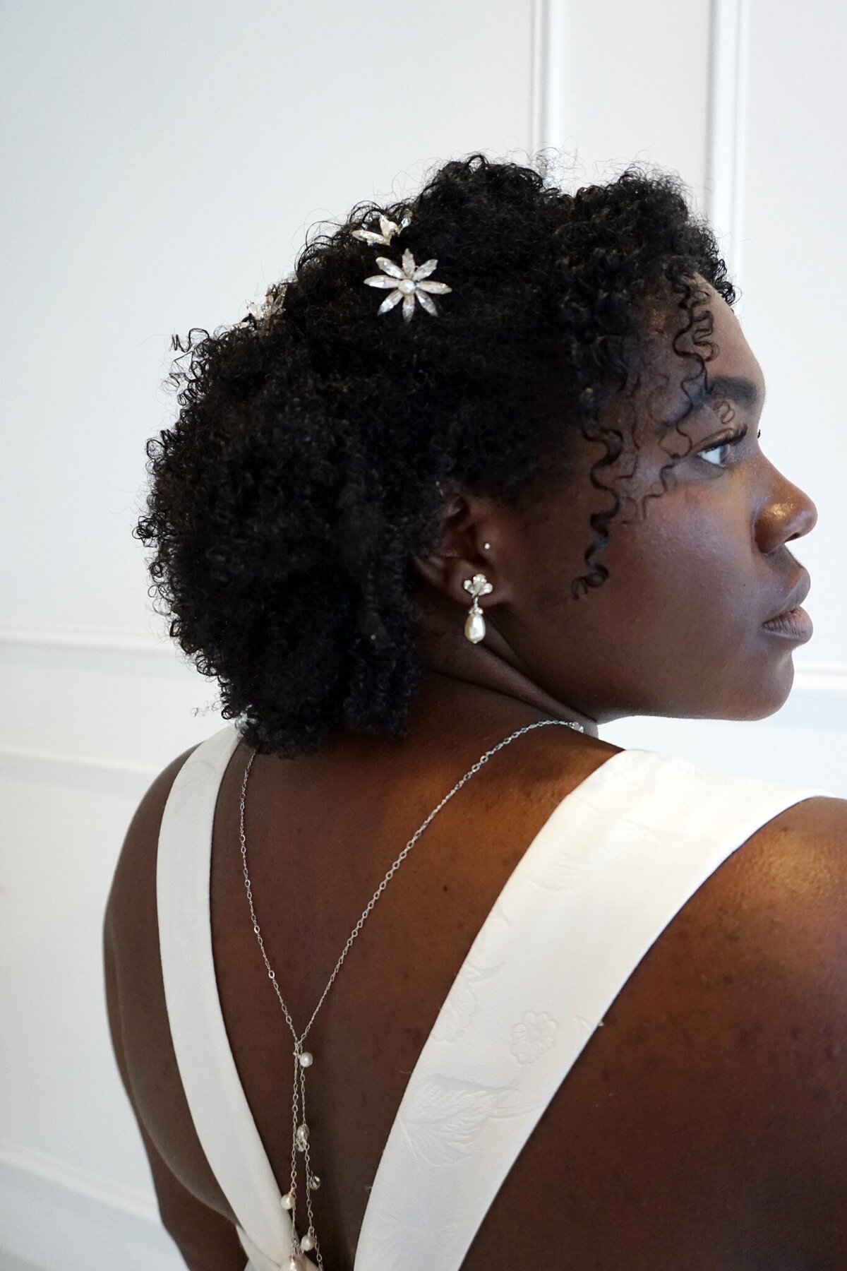Back close-up of a black model in the Sol wedding dress style with a back necklace, earrings, and hair accessories by Ti Adoro.