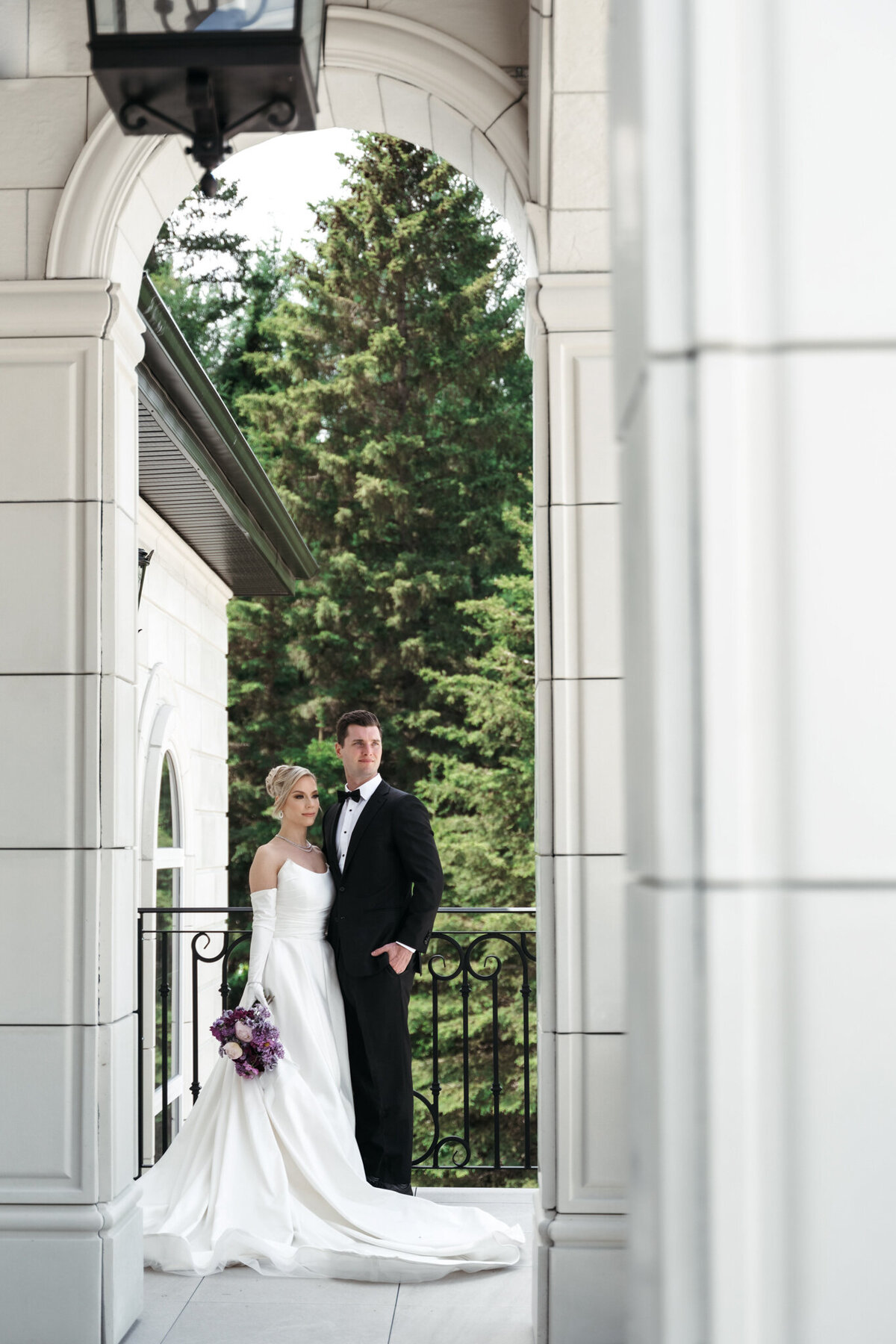 Couple standing in stunning arch at Archway Manor Weddings & Events, elegant, timeless, European-inspired Red Deer, Alberta wedding venue, featured on the Brontë Bride Vendor Guide.