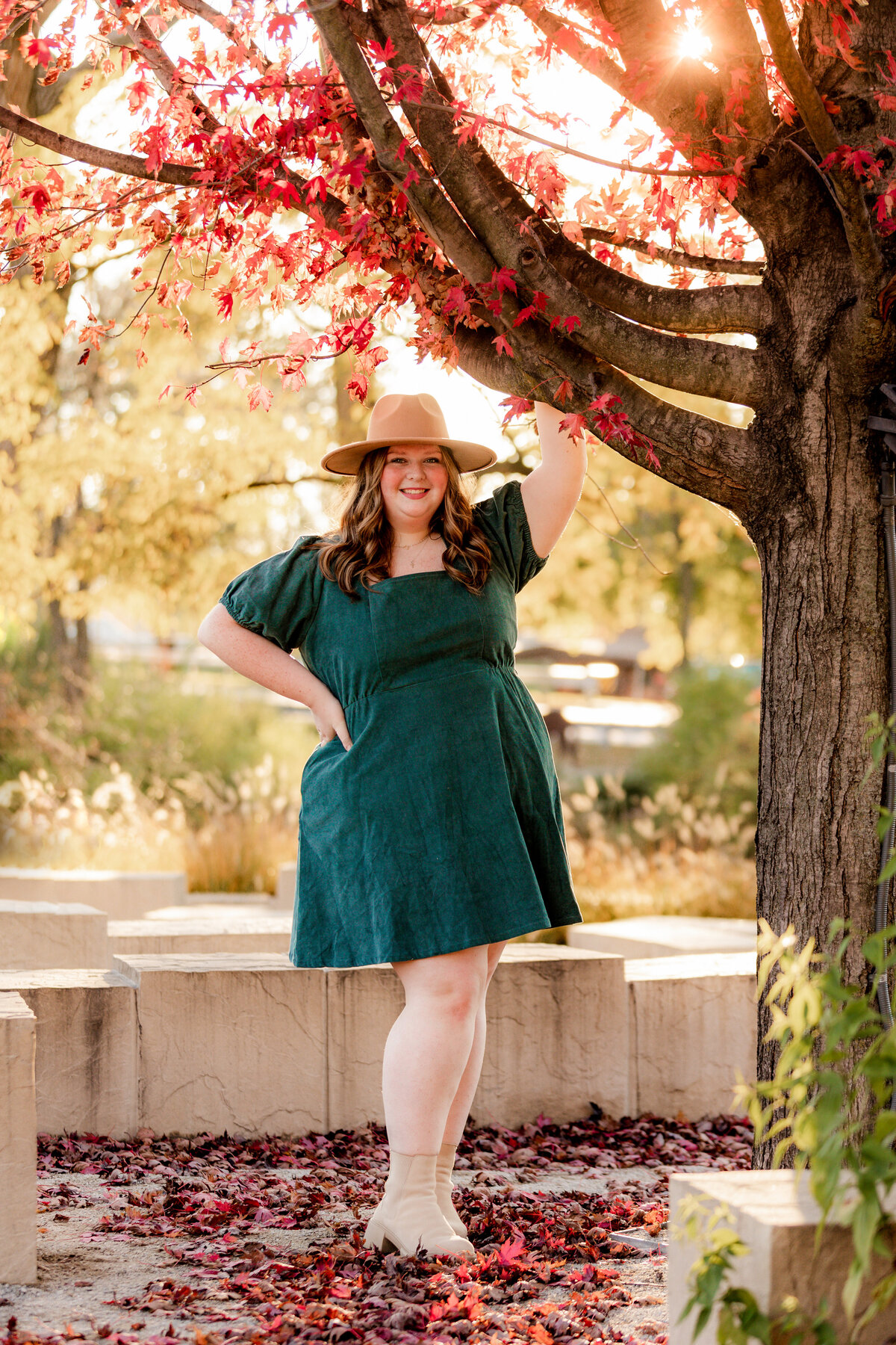 Claire leans her arm up on a tree with her right hand to her hip during her fall photo session.