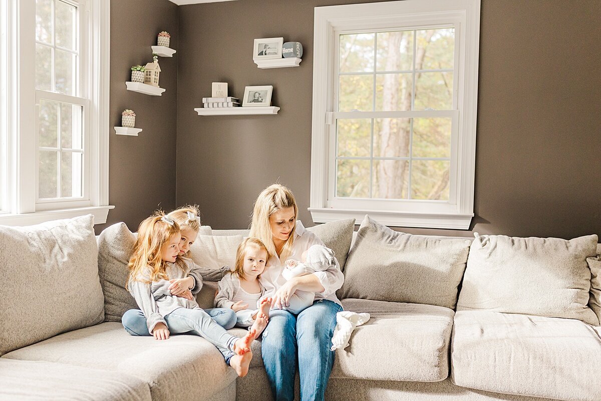 mom sits on couch with kids  during in home newborn photo session with Sara Sniderman Photography in Sherborn Massachusetts