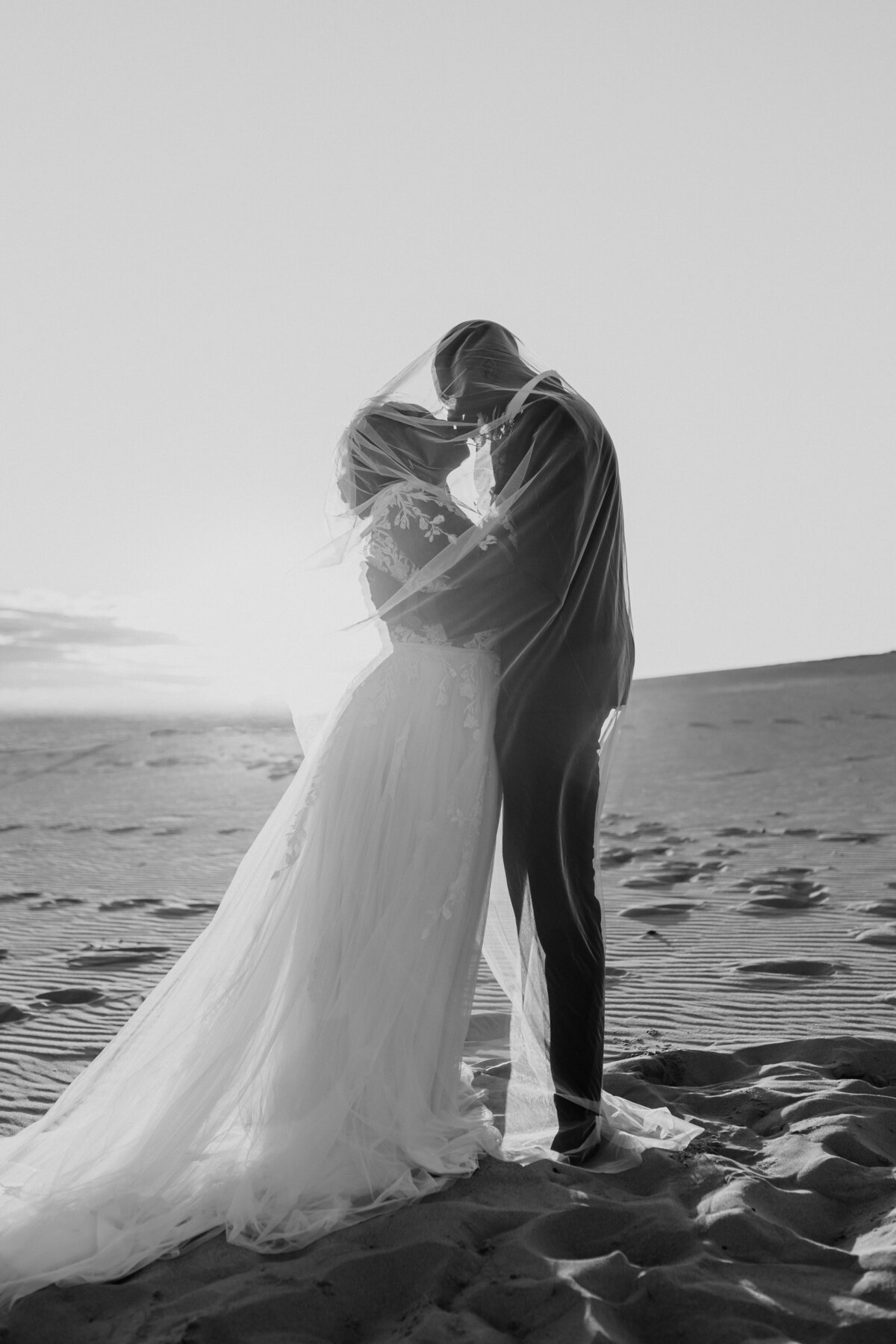 black and white photo of elopement wedding couple in the sand dunes at sunset