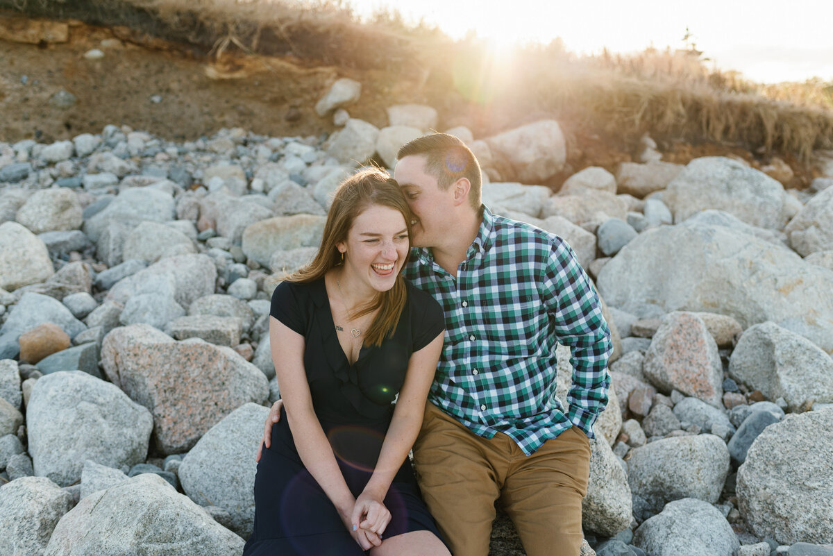 Joyful couple sitting on the rocks at sunset.