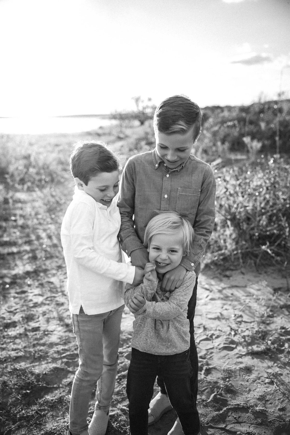 three brothers are playing and laughing while they tickle each other