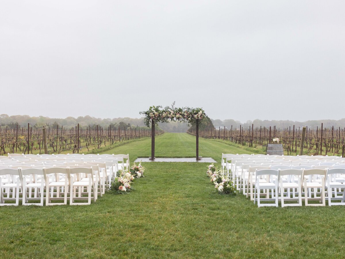 A floral arch in a foggy vineyard wedding.