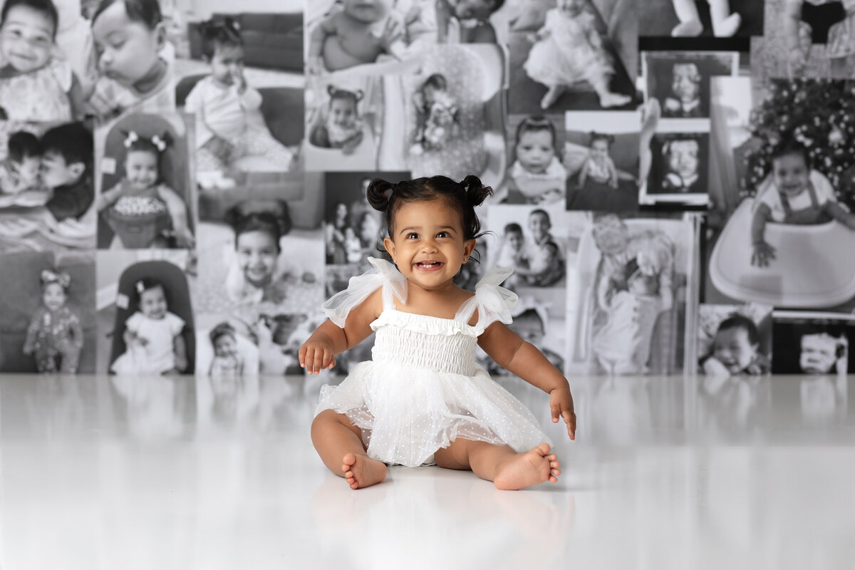 One year old Tampa baby enjoying a personalized luxury cake smash session with elegant black and white photo decorations
