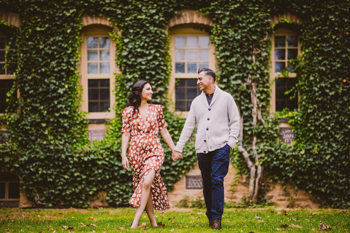 An engagement couple walking at princeton university in front of the vine walls