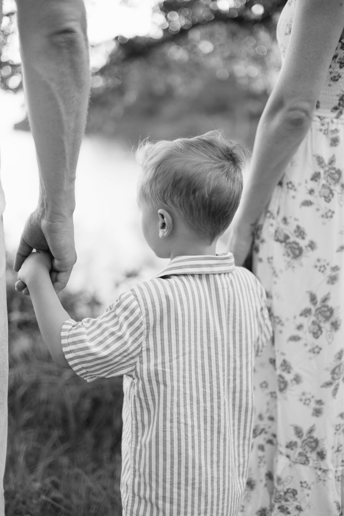 A young boy holding hands with his mom and dad during their family session in Flower Mound, TX