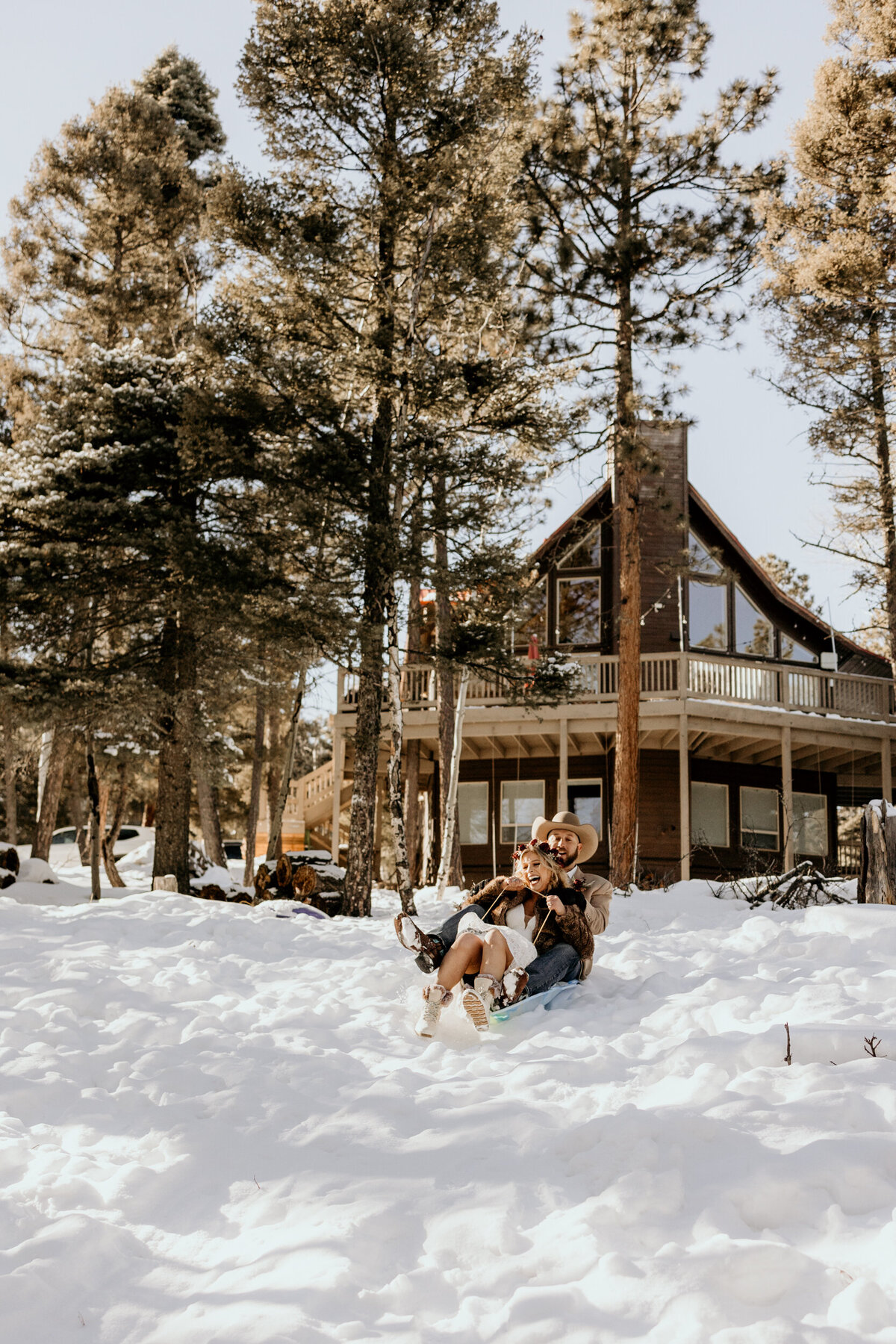 Bride and groom sledding on a hill in Angel Fire, New Mexico