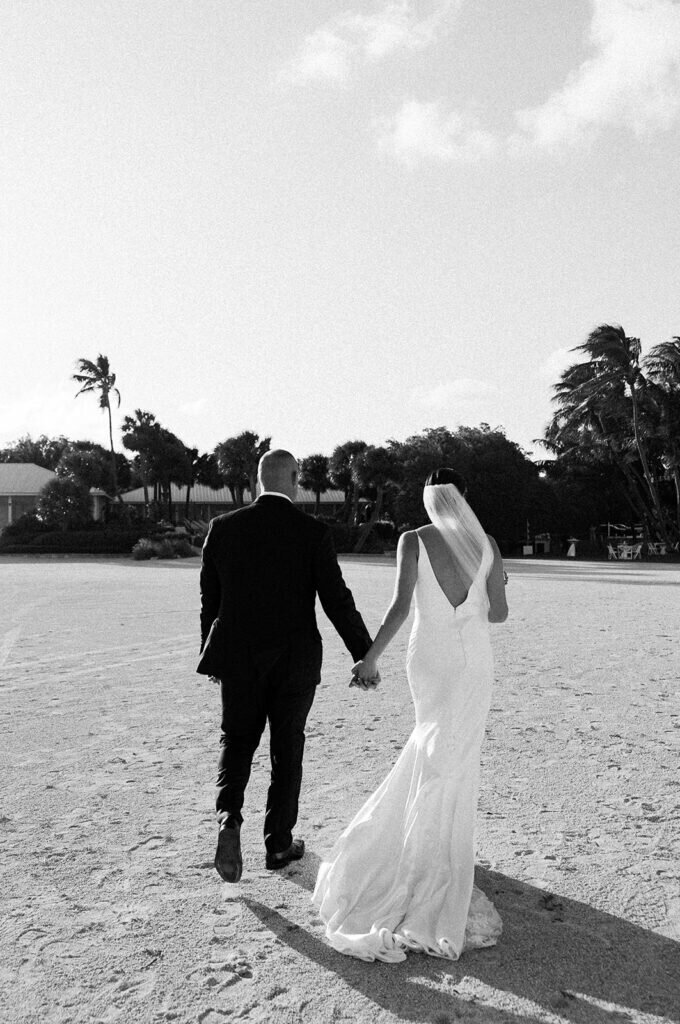 A romantic black-and-white moment as the newlyweds walk together on the sandy shore, enjoying their first moments as husband and wife. Captured by Claudia Amalia Photography, a Florida Keys wedding photographer specializing in destination wedding photography.