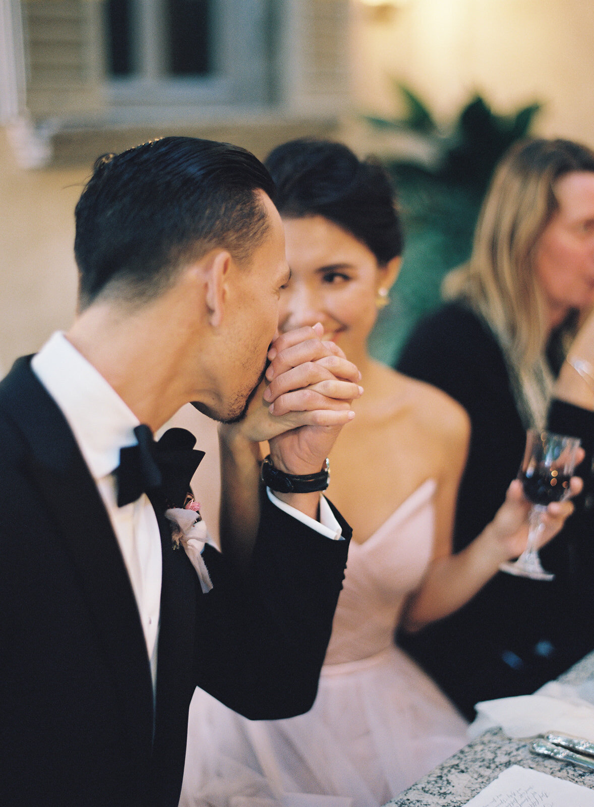 groom kisses bride's hand at reception