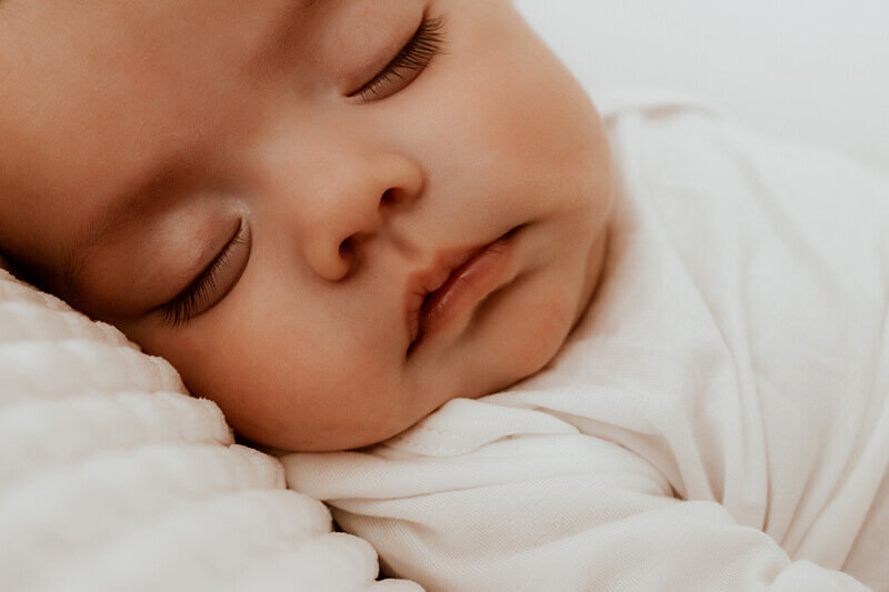 Newborn baby girl sleeping on a white blanket