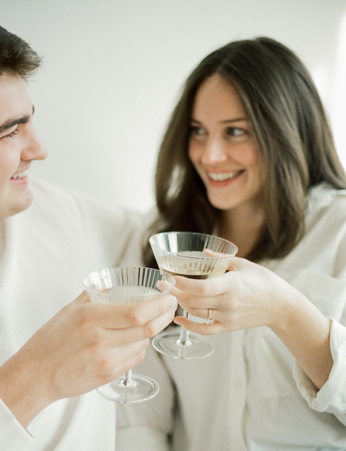 soft film couple photography, cheers with champagne coupes, white natural light studio