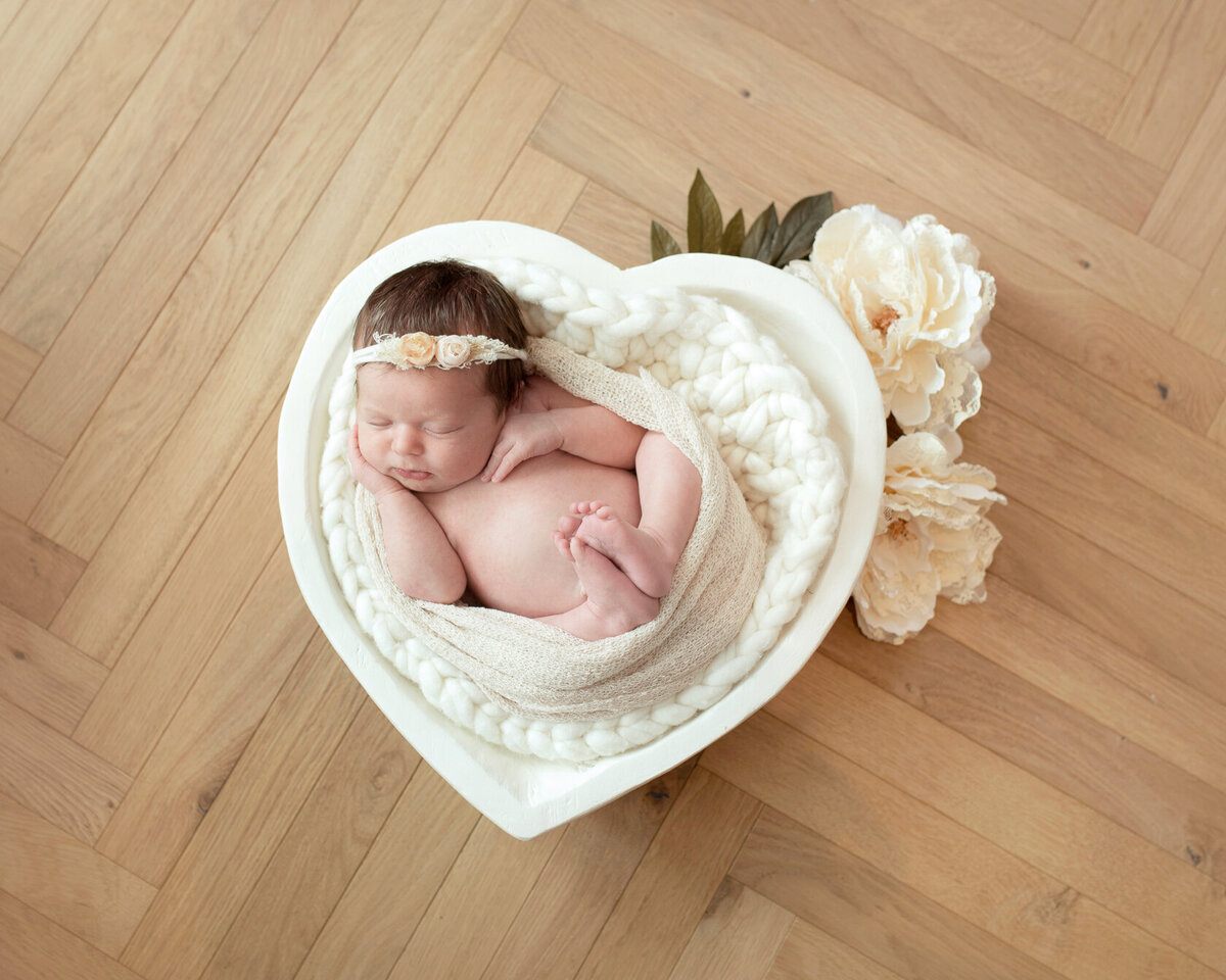 Newborn in white flower heart-shaped bucket