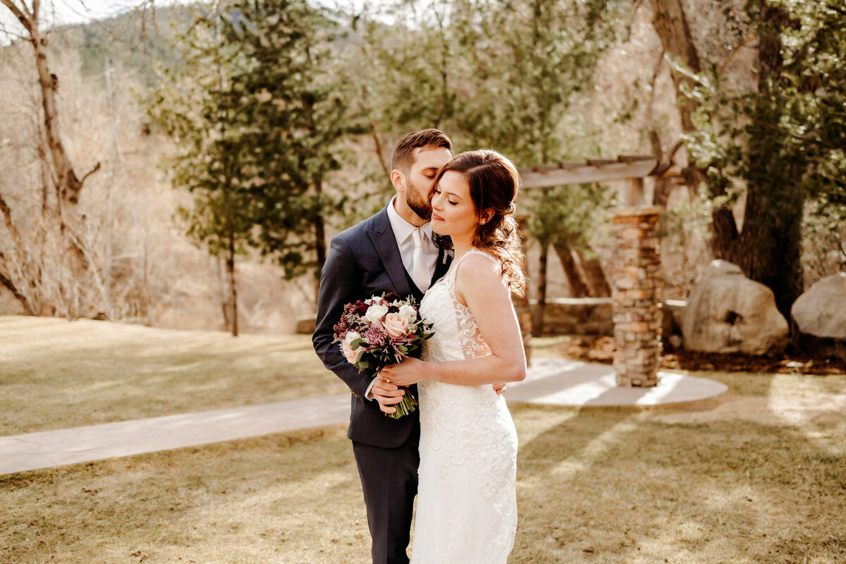Husband kissing his new bride on grassy lawn in Boulder Colorado 