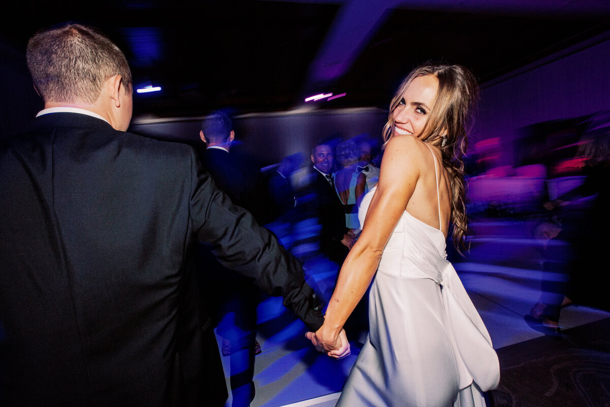 A vibrant wedding reception moment with the bride and groom dancing under colorful lights, celebrating their special day with joy and laughter.