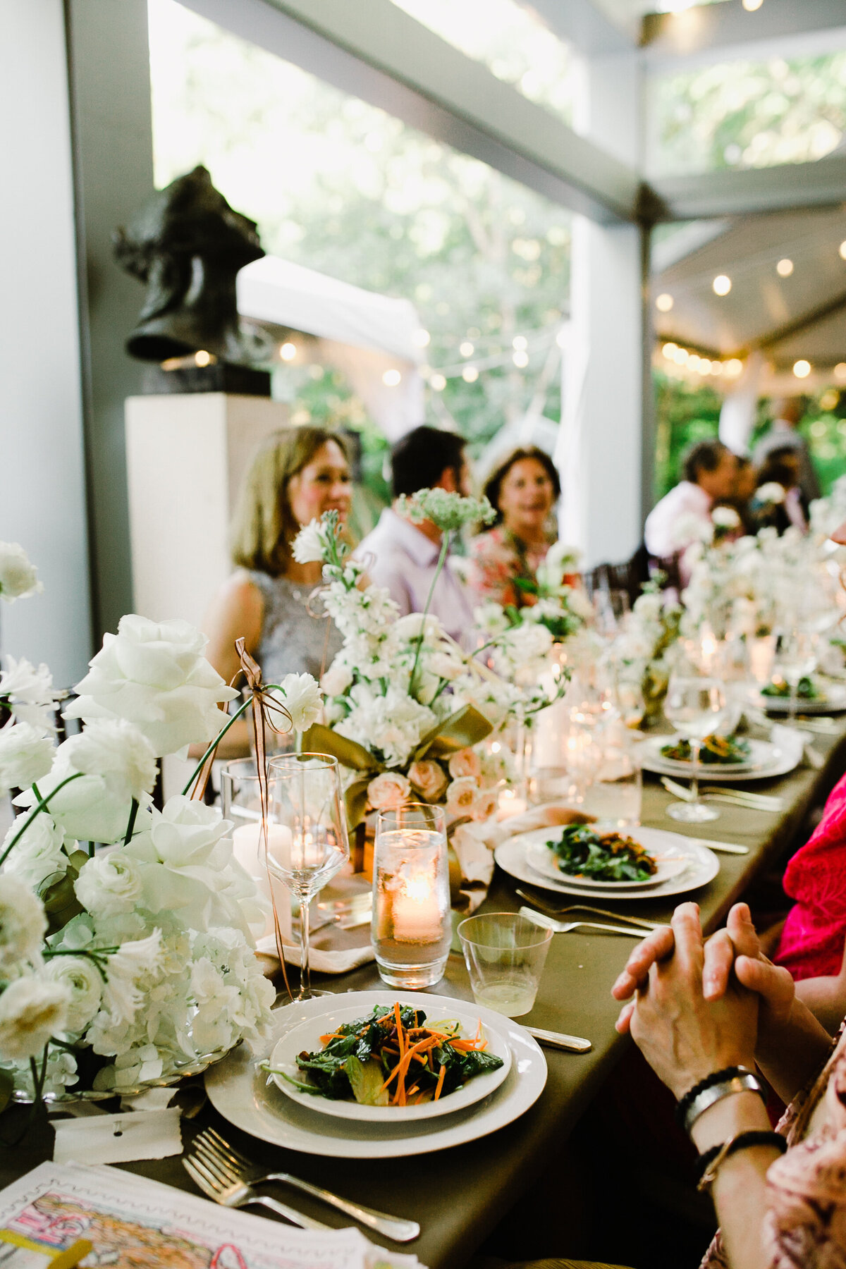 Guests at wedding reception table decorated with white florals and candles