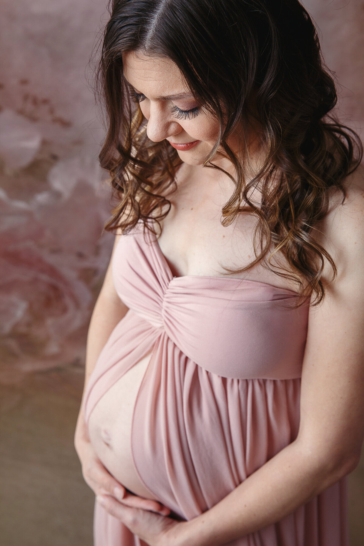 Beautiful pregnant woman looking down at her baby bump