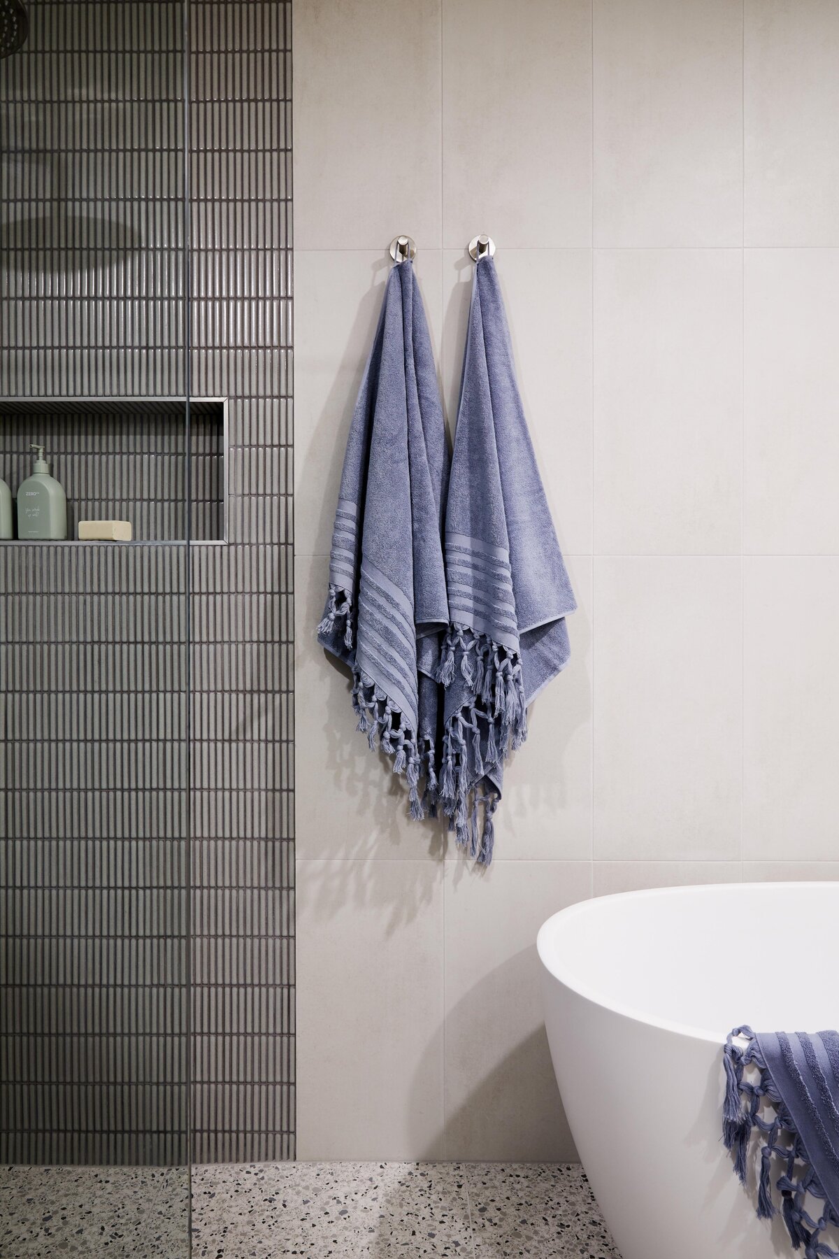 Detail of Elwood apartment bathroom with freestanding bathtub, terrazzo flooring and blue towels