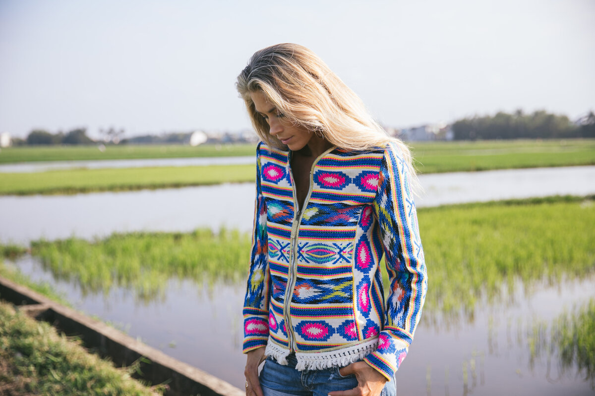 Picture of woman wearing patterned jacket in flooded rice fields