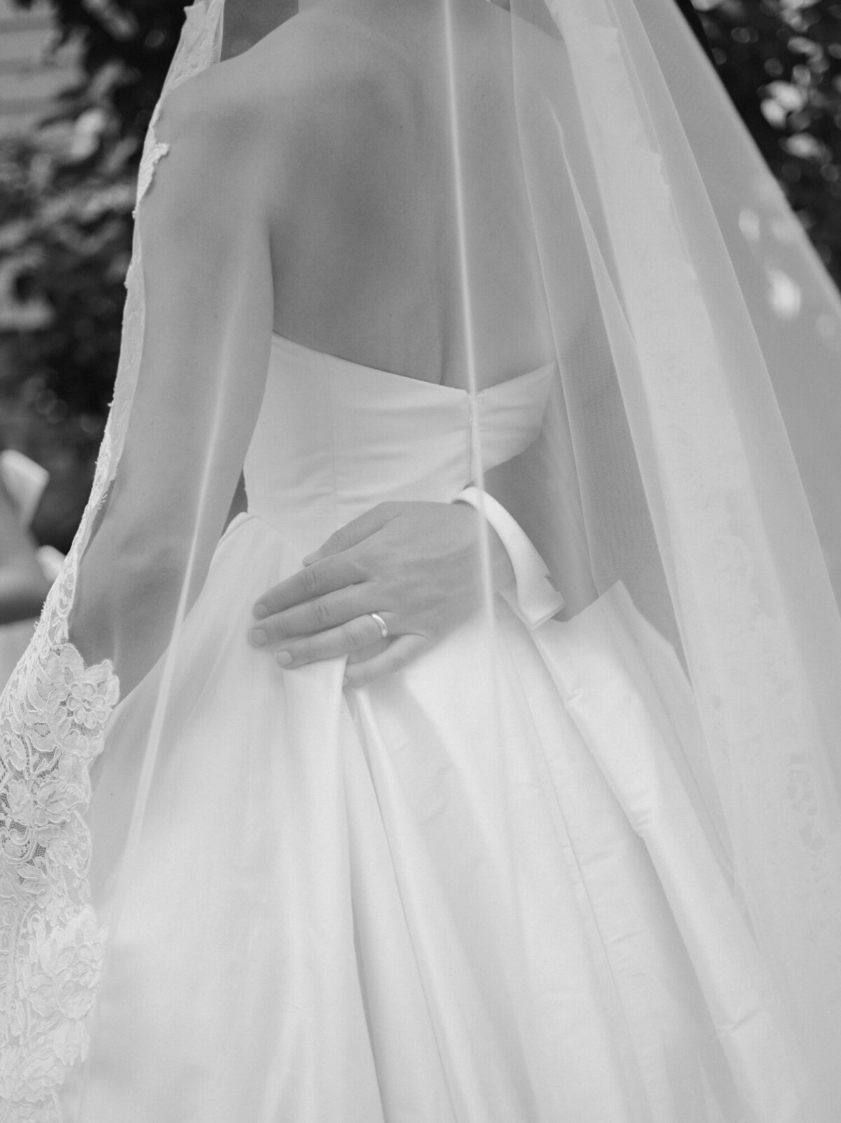 soft film wedding photo of a groom holding his bride's waist under her veil