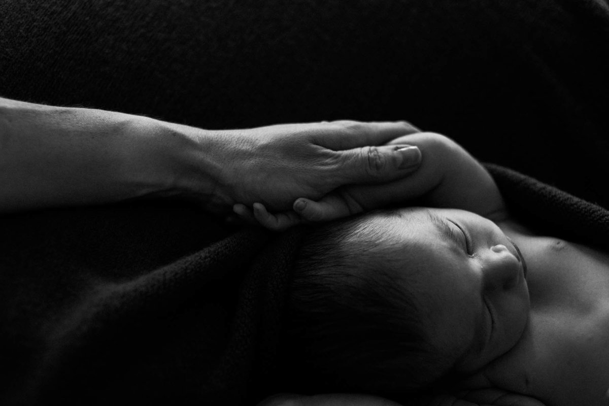 mother holding newborns arm during a photo session with Laurie Baker