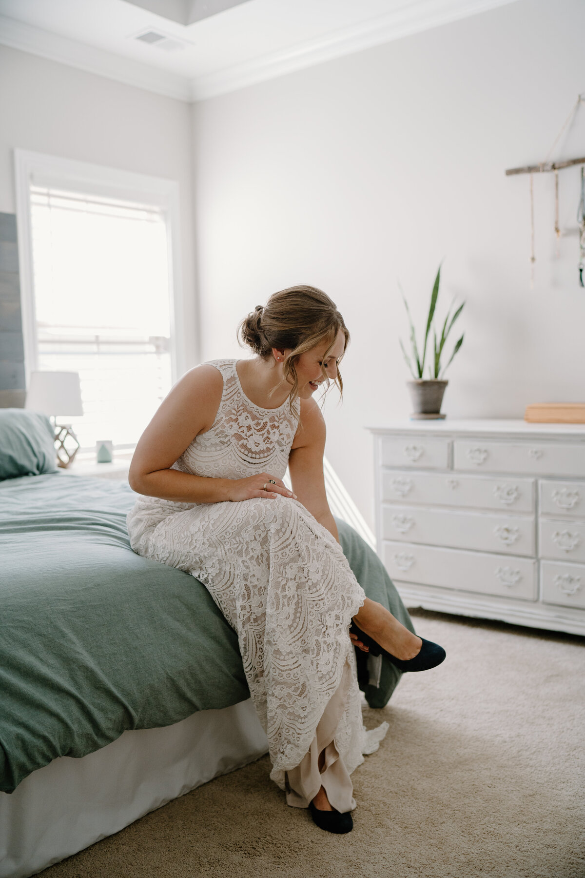 Bride putting on shoes sitting on bed