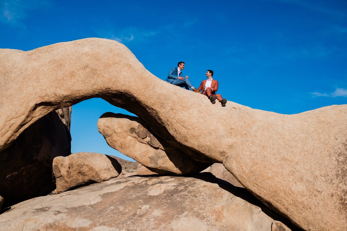 Two grooms sit on Arch Rock in Joshua Tree National Park.