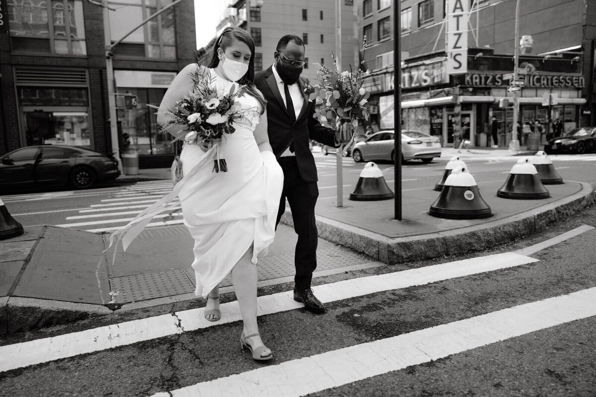Black and white photo of the bride and the groom crossing E. Houston Street in New York City.