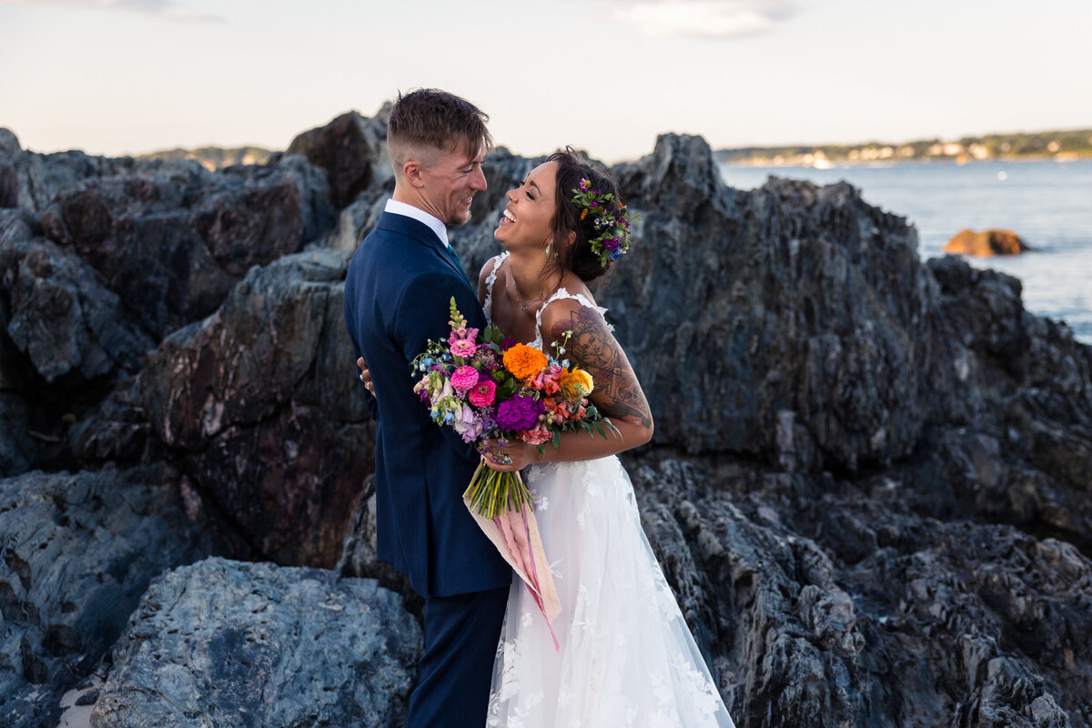 Bride and groom laughing on beach during wedding portraits.