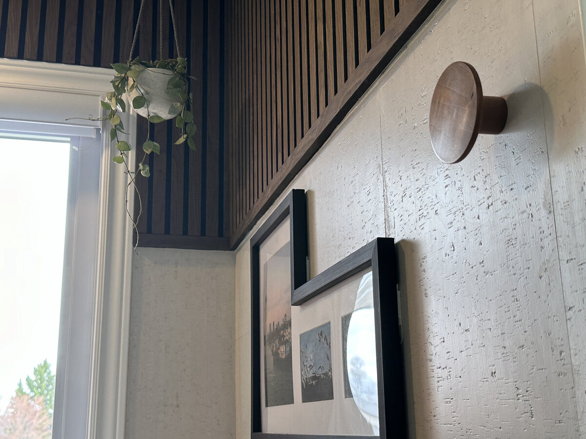 Detail of hanging plant and framed artwork on walls dressed with cork tiles and walnut slats in this modern home office, designed and installed by Urbanomic Interiors in Barrhaven (Ottawa).