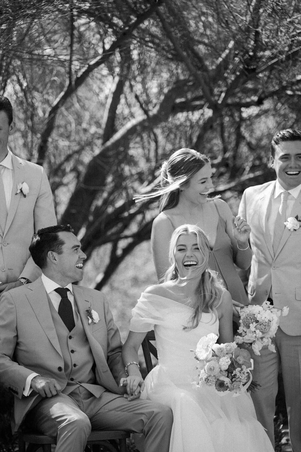 Bride and groom laughing with their wedding party during portraits at El Chorro, captured by a Scottsdale wedding photographer.
