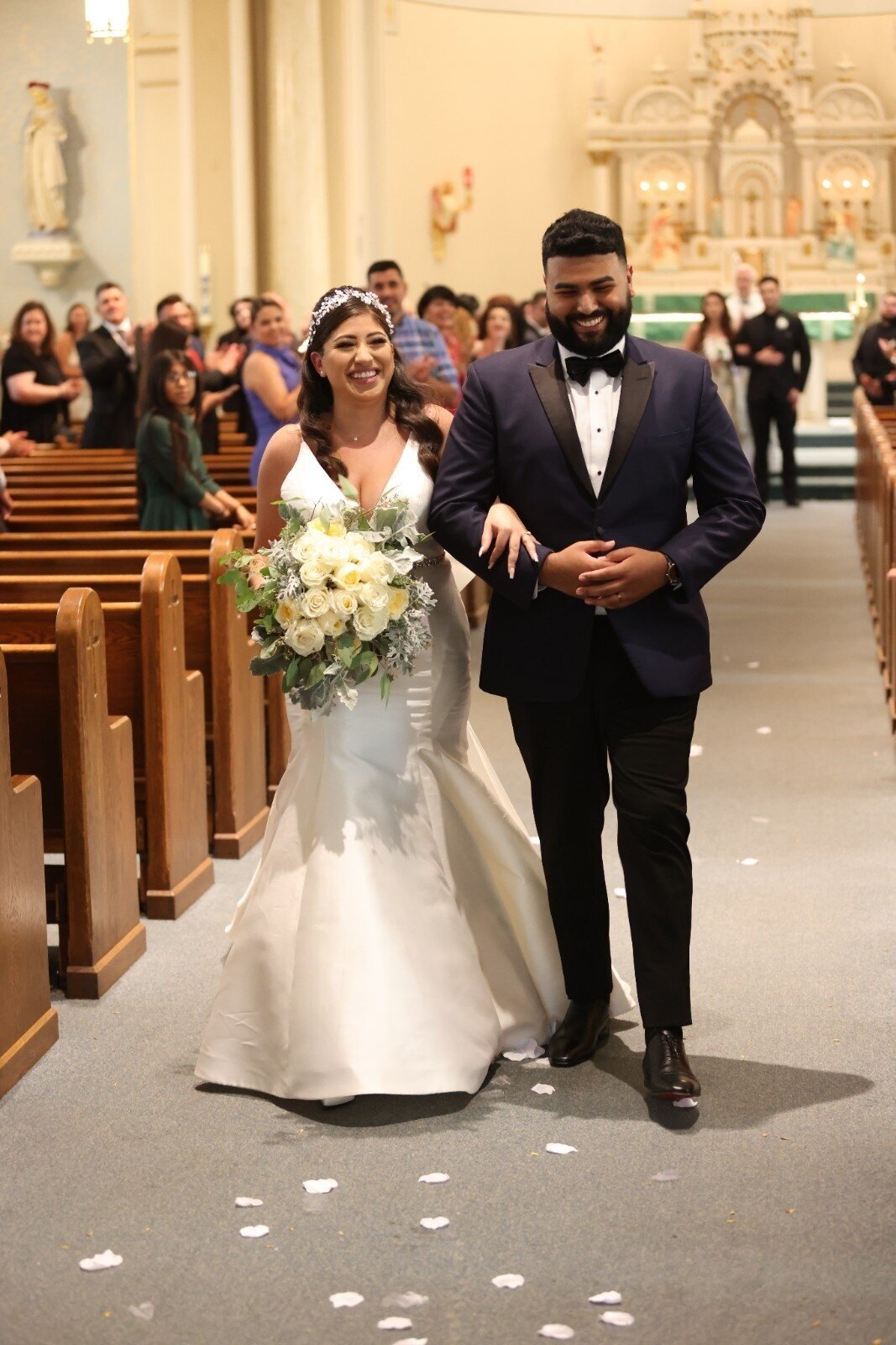 Bride and groom walk down church aisle as newlyweds