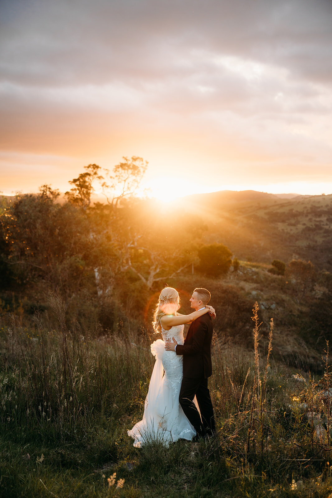 Sunset wedding photos at Brindabella Hills Winery. Couple hold each other and look over to the sunset across the Murrumbidgee River
