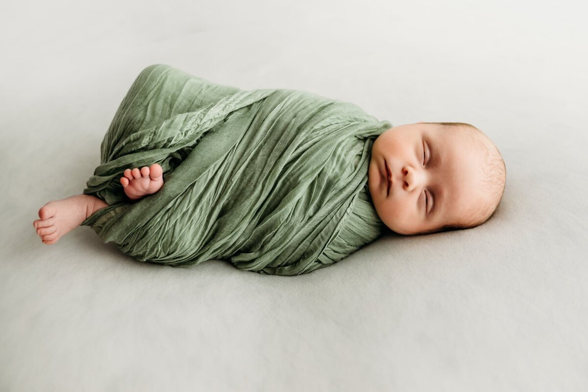 baby in green wrap with feet sticking out