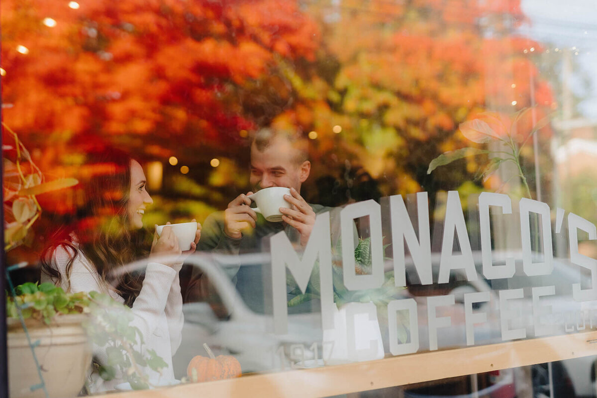 Couple looking at each other sipping coffee  viewed through the window t Finger Lakes engagement session