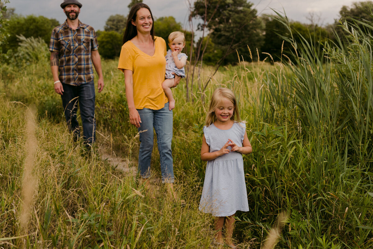 family walking through tall grass in the summer together