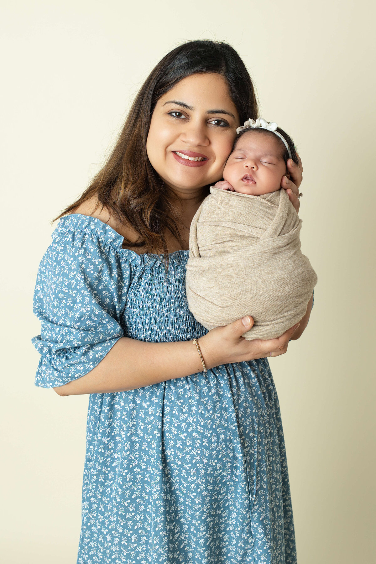 mom holding newborn baby girl with her cheek pressed to sleeping baby's cheek