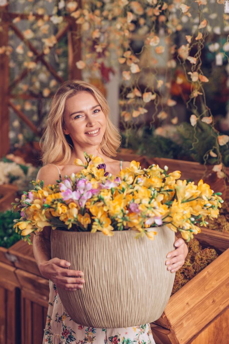 portrait-blonde-smiling-young-woman-holding-large-pot-yellow-flowers