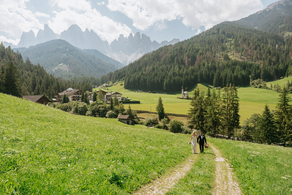 Couple holding hands on mountain trail with Dolomites view