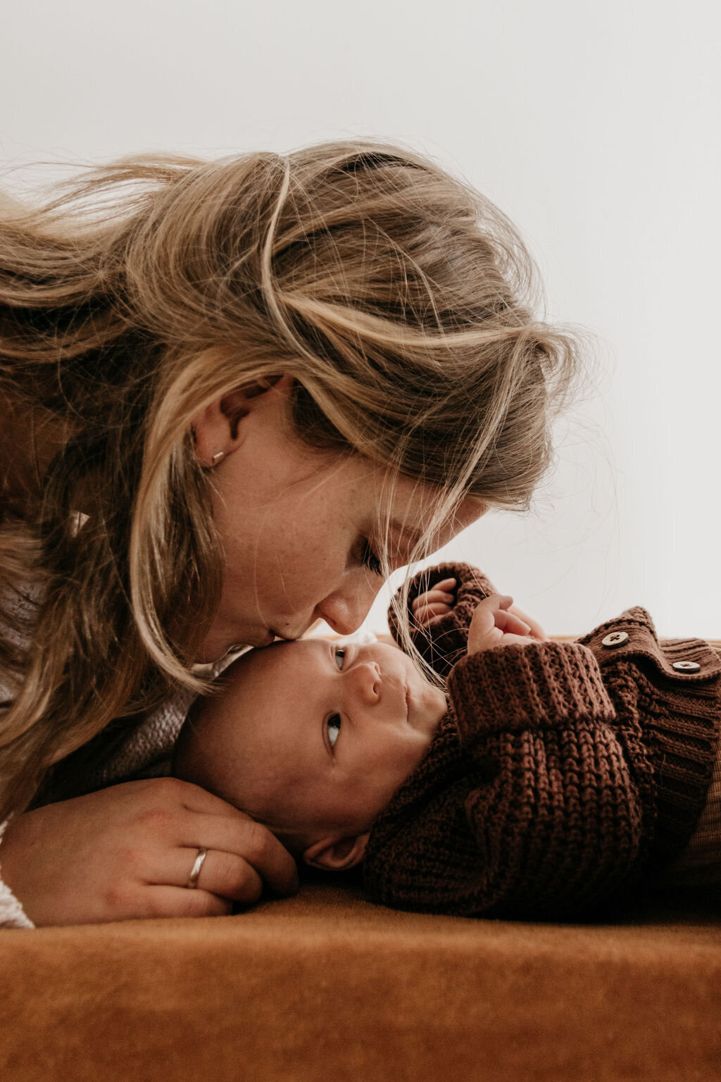 Moeder geeft newborn baby  kusje tijdens de newbornshoot