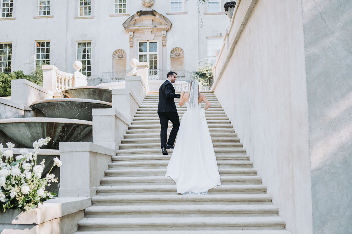 bride and groom hold hands while they walk up stairs to the Swan House wedding venue