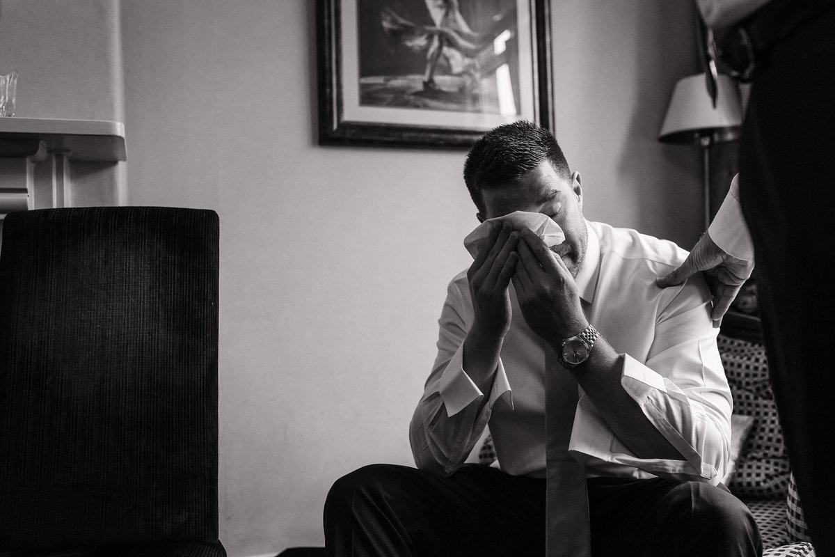 Black and White photo of a groom crying after reading his wife to be’s card
