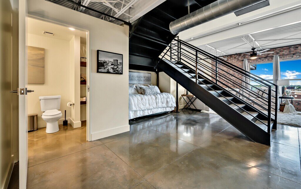 View of the main level including half bath and beautiful staircase in this 2 bedroom, 2.5 bathroom luxury vacation rental loft condo for 8 guests with incredible downtown views, free parking, free wifi and professional decor in downtown Waco, TX.