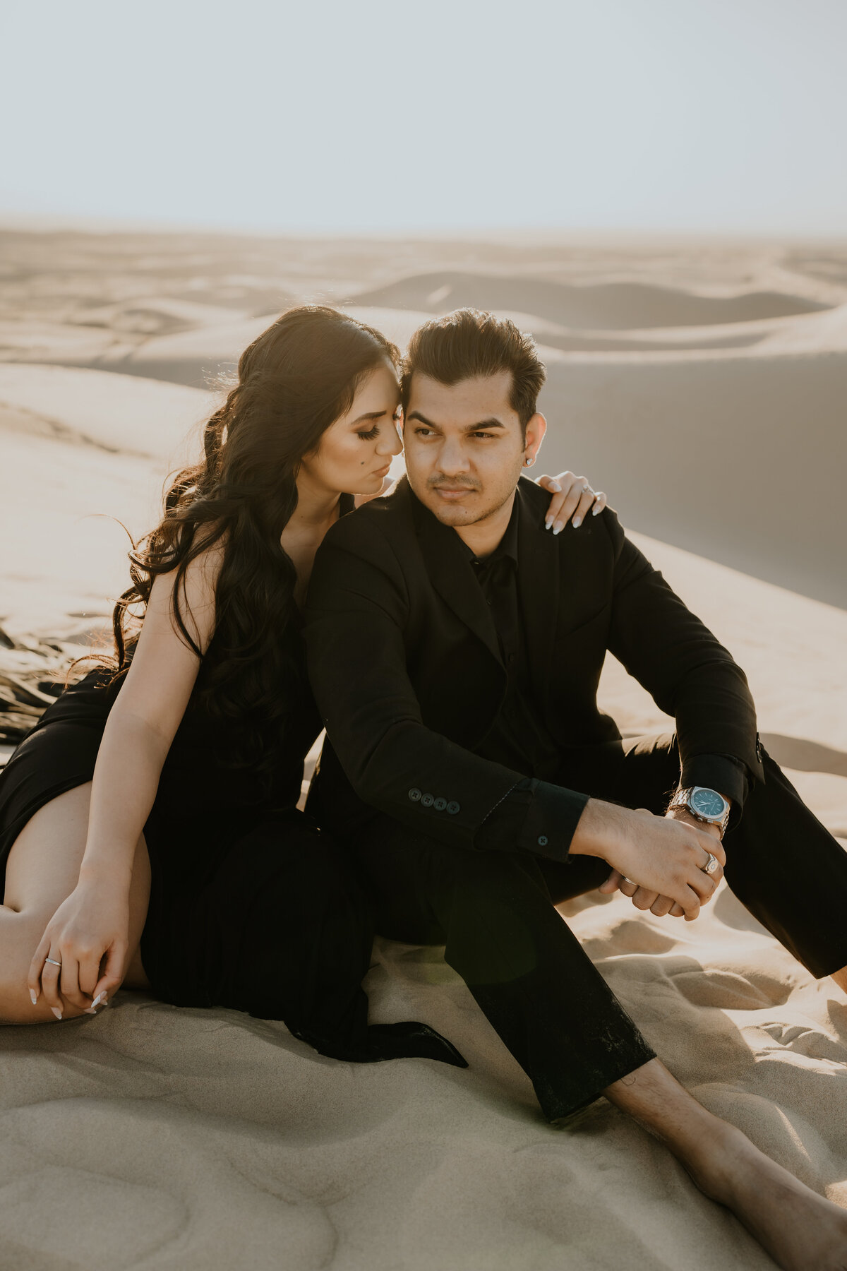 man and woman sit on the sand in the desert