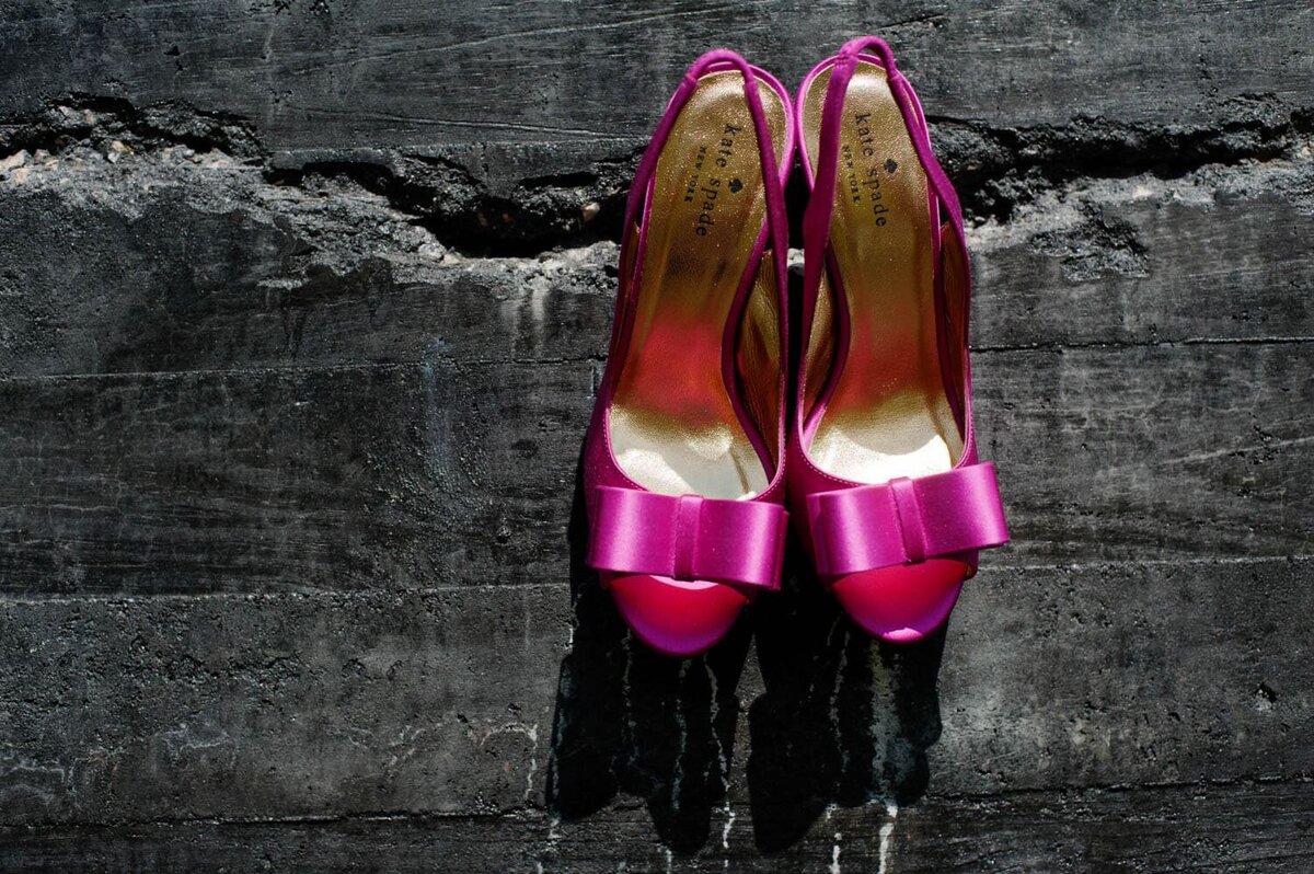 hot pink kate spade heels hang from a black stone wall